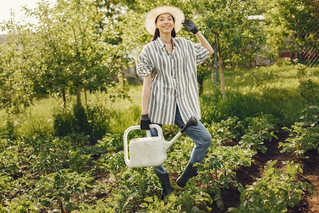 Foto gratuita la donna in un cappello che tiene imbuto e lavora in un giardino