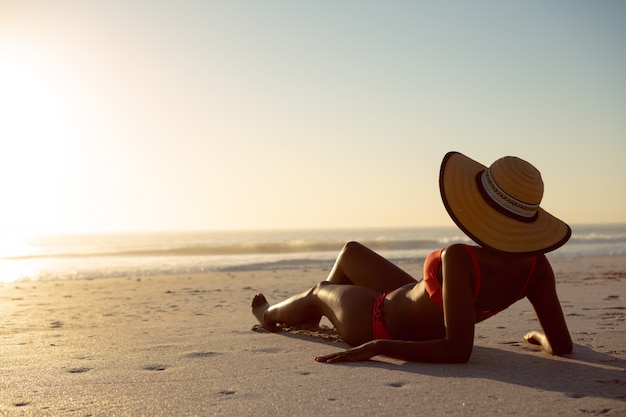 Foto gratuita donna con cappello rilassante sulla spiaggia