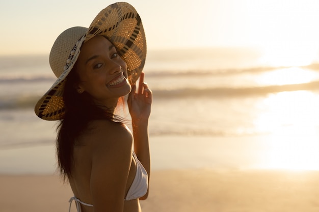 해변에 서있는 모자에있는 여자