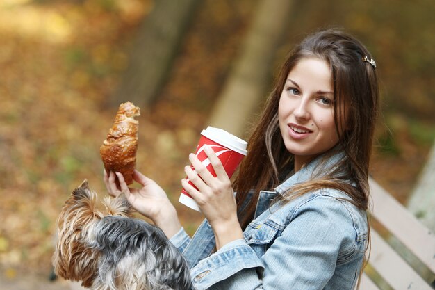 女性は彼女の犬と散歩しながら昼食をとる