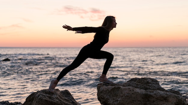 Woman having a challenging position on a coast