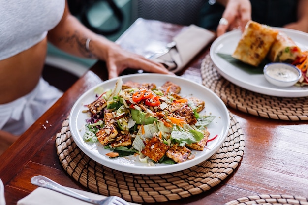 Woman having colorful healthy vegan vegetarian meal salad in summer cafe natural day light