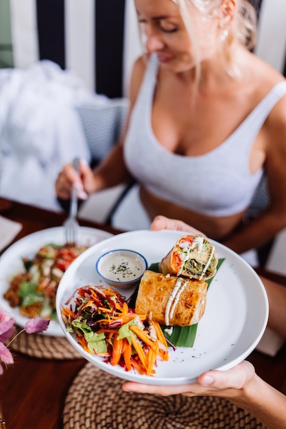 Woman having colorful healthy vegan vegetarian meal salad in summer cafe natural day light