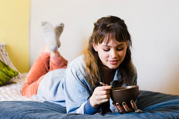 Woman having food on bed