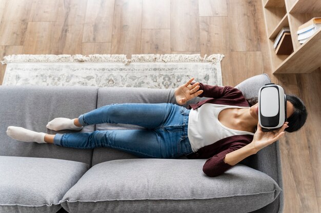 Женщина весело дома на диване с гарнитурой виртуальной реальности