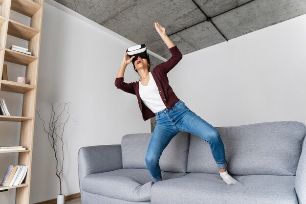 Женщина весело дома с гарнитурой виртуальной реальности
