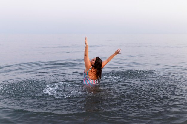 Женщина с удовольствием в воде на пляже