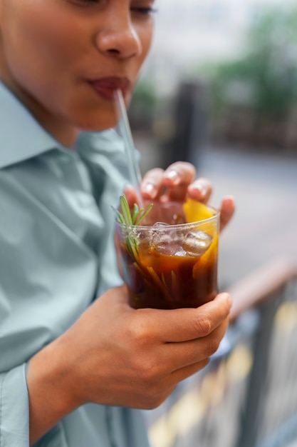 外でアイスコーヒーを飲む女性