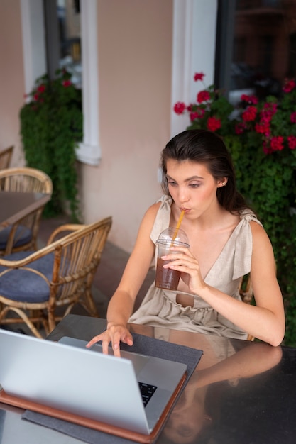 ノートパソコンを使用中にアイスコーヒーの休憩をとっている女性