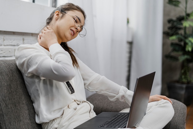 Woman having a neckache as she works at home