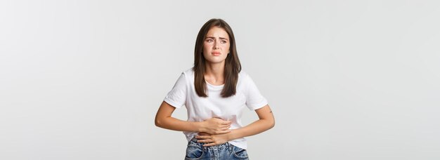 Woman having stomach ache bending and holding hands on belly discomfort from menstrual cramps