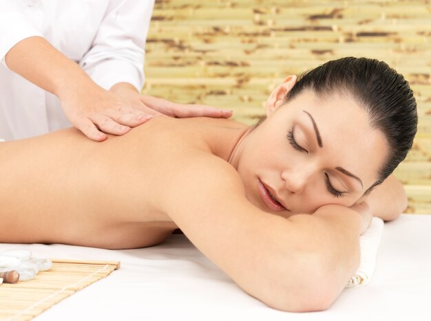 Женщина, имеющая терапевтический массаж спины в спа-салоне. Концепция лечения красоты.