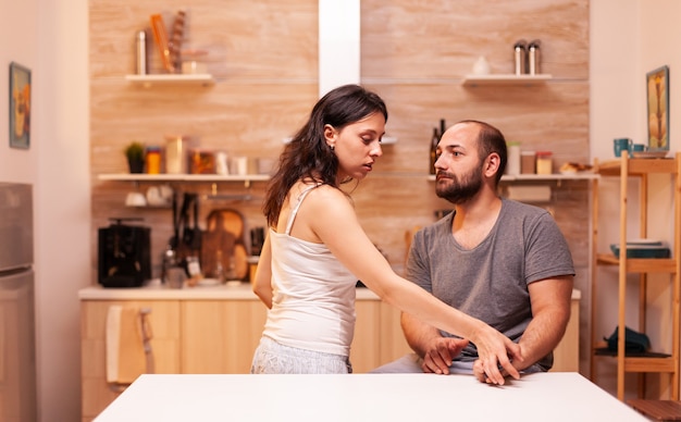 Woman having trust issues because if infidel husband and trying to read his phone messages. Heated angry frustrated offended irritated accusing her man of infidelity .