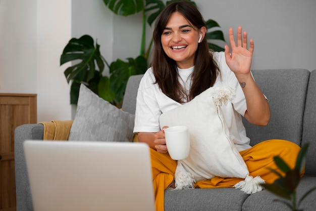 Free photo woman having a video call at home on a laptop device