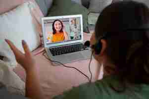 Foto gratuita donna che fa una videochiamata a casa su un portatile con cuffie