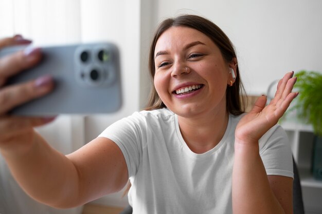 スマートフォンで自宅でビデオコールをしている女性