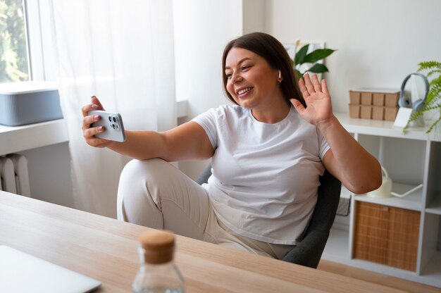 Женщина ведет видеозвонок дома с помощью смартфона