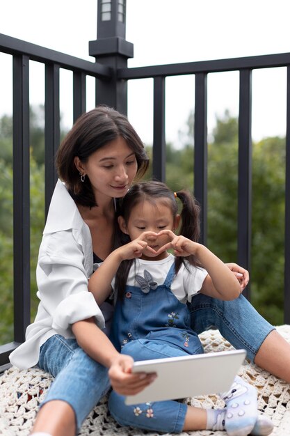 Woman having a video call with her husband next to their daughter outdoors