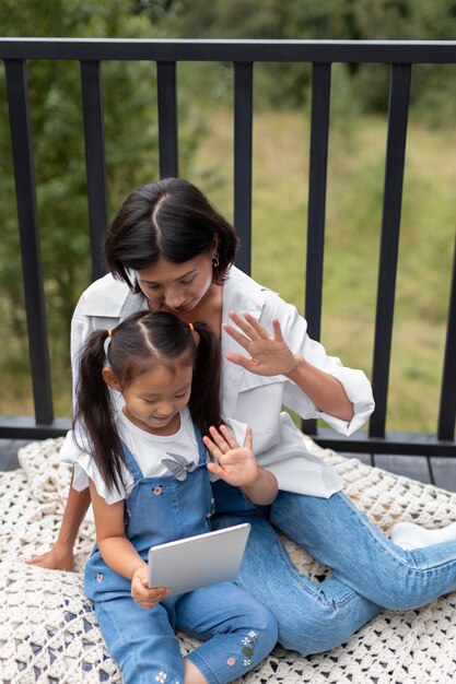 Woman having a video call with her husband next to their daughter outdoors