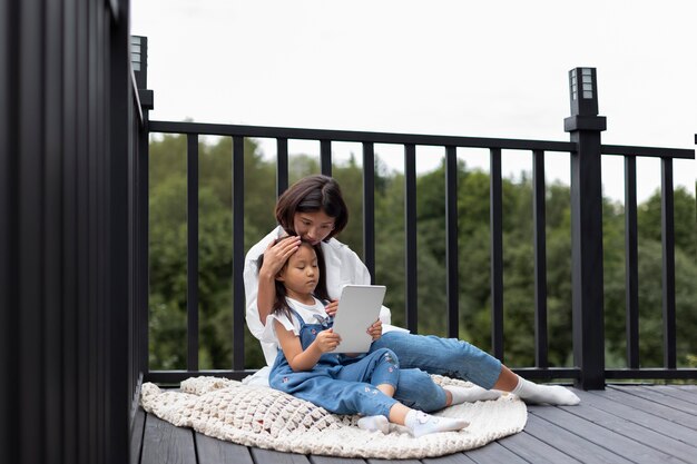 Woman having a video call with her husband next to their daughter outdoors