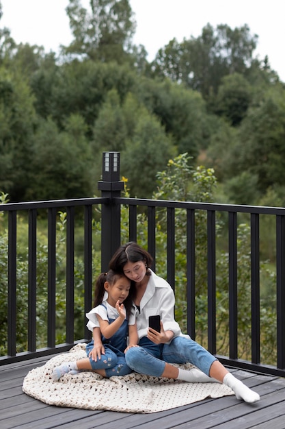 Woman having a video call with her husband next to their daughter outdoors