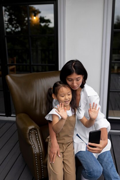 Woman having a video call with her husband next to their daughter outdoors