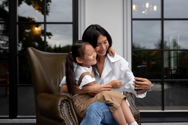 Woman having a video call with her husband next to their daughter outdoors