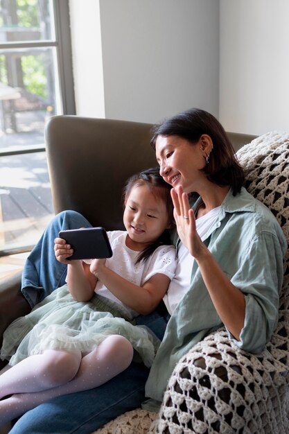 Woman having a video call with her husband next to their daughter