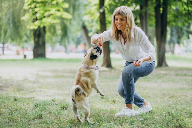 Donna che ha una passeggiata nel parco con il suo animale domestico del pug-dog