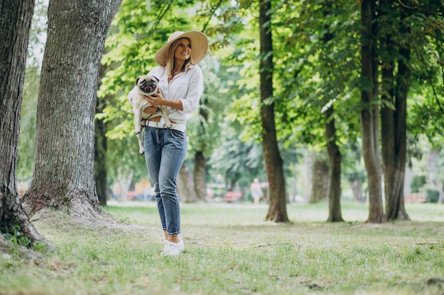 Женщина гуляет в парке со своим питомцем мопса