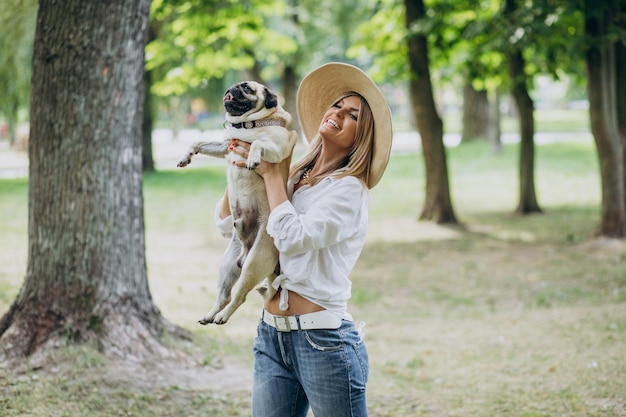 Woman having a walk in park with her pug-dog pet