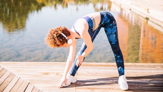 Woman in headphone exercising on pier