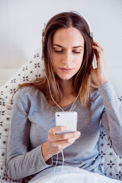 Woman in headphones browsing smartphone