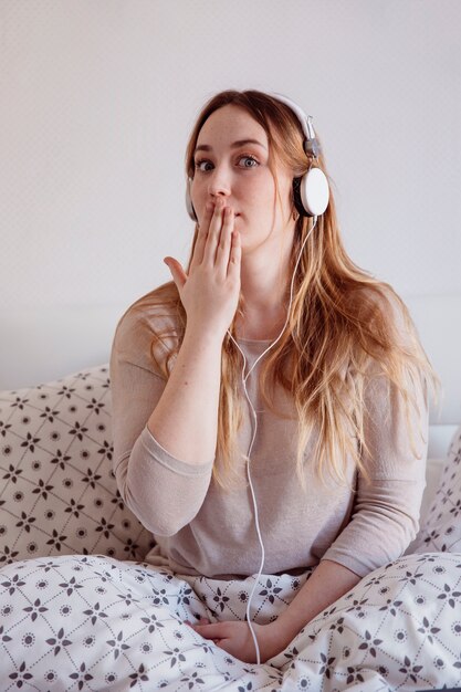 Woman in headphones covering mouth