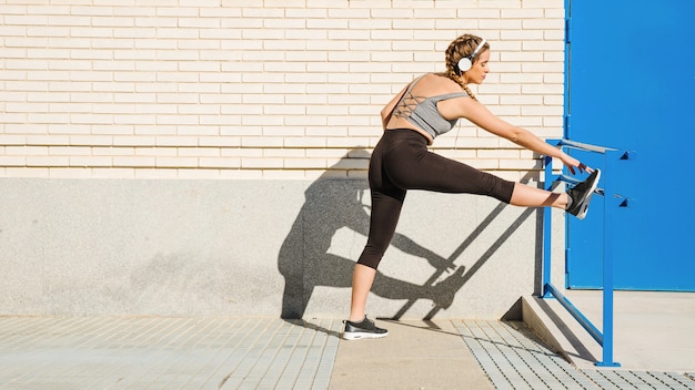 Woman in headphones exercising near building