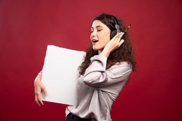 Woman in headphones holding canvas and listening to song.