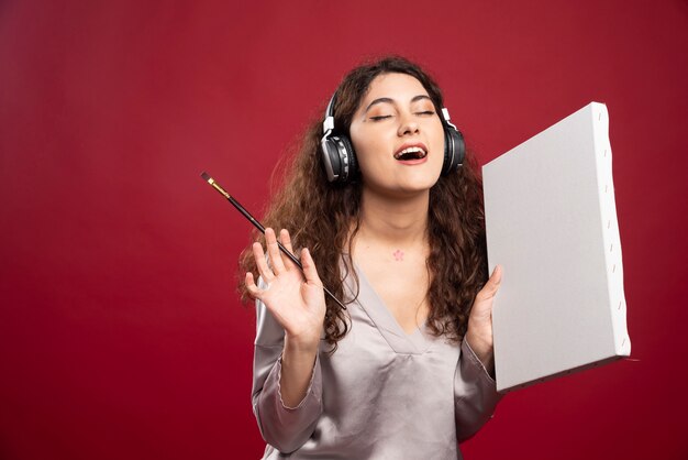 Woman in headphones posing with brush and canvas.