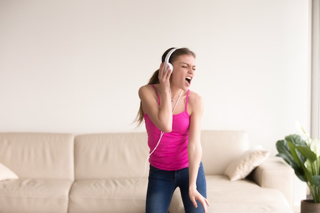 Free photo woman in headphones singing and dancing at home