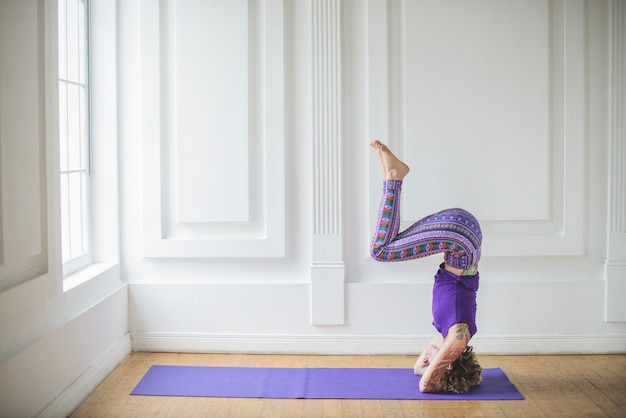 Woman in headstand on stretching mat