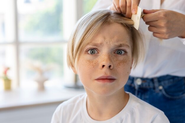 Woman helping boy with lices front view