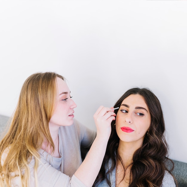 Женщина помогает другу нанести макияж
