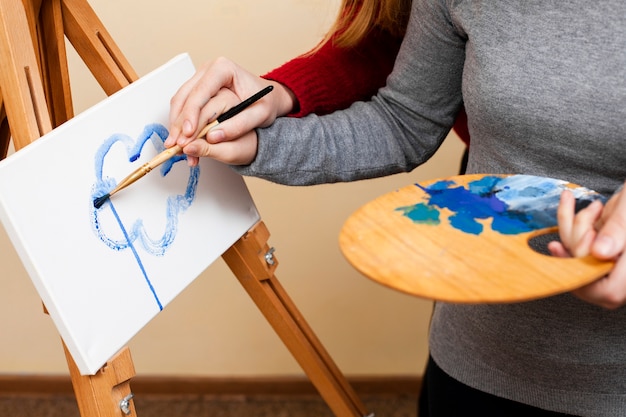 Free photo woman helping girl with down syndrome paint