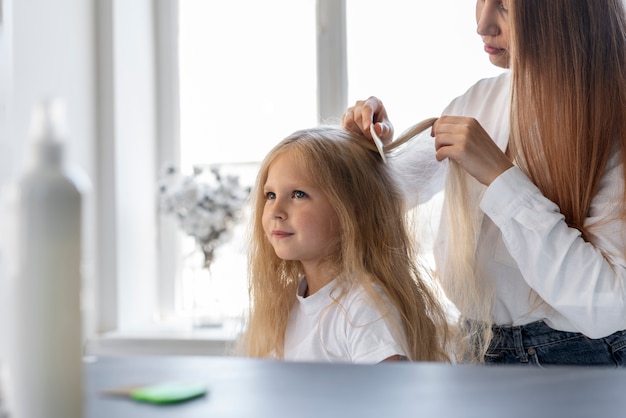 Woman helping girl with lices side view