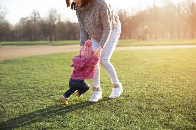Женщина помогает ребенку гулять на свежем воздухе
