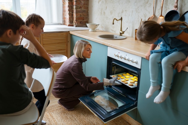 Woman helping kids bake cookies side view