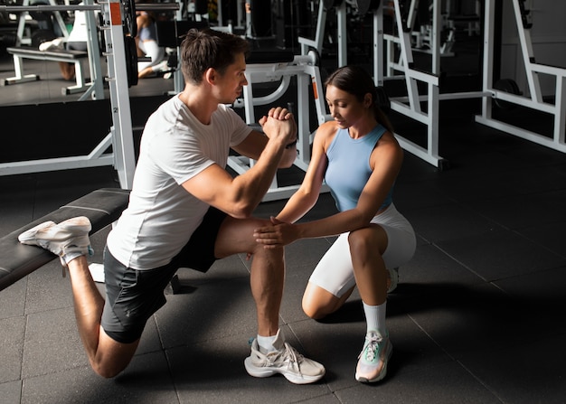 Woman helping man at gym