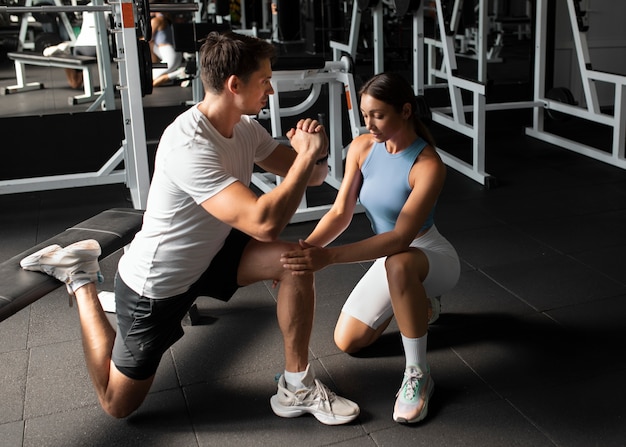 woman helping man at gym