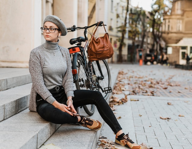 Woman and her bike sitting on the stairs in front of building