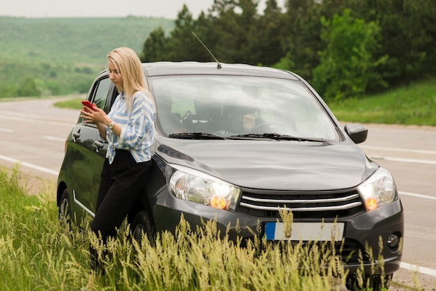 Foto gratuita donna accanto alla sua automobile analizzata