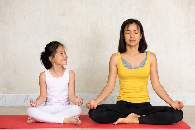 Woman and her charming little daughter doing meditation